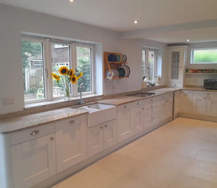 Bright kitchen with white cabinets, beige countertops, and sunflowers in a vase by the window