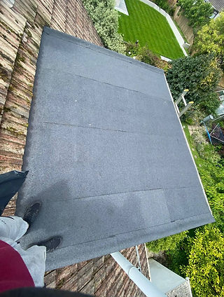 A newly installed grey felt flat roof looking down into a green garden