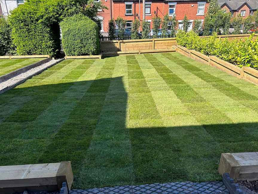 freshly laid turf with lawn stripes in garden with wooden sleeper borders
