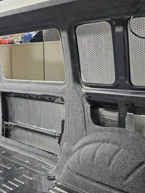 Interior of a van in progress showing carpeted wheel arches