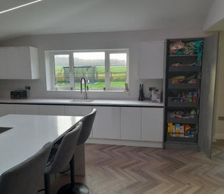Modern kitchen with white cabinets and island, open pantry with snacks