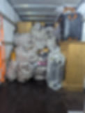The inside of a removal lorry packed with checked laundry bags wooden furniture