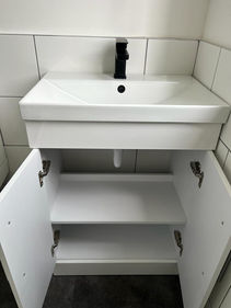 White bathroom vanity unit with open doors showing interior shelves and sink
