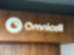 Illuminated "Omnicell" sign on a wood-panelled wall. The sleek