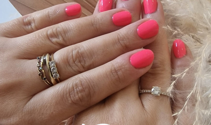 Vibrant bright pink gel manicure on manicured hands with gold rings at HB Therapy nail barS