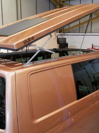 High angle view of a bronze camper van having a pop top roof installed in a workshop