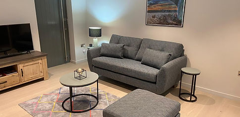 Modern living room featuring grey sofa coffee tables and TV media unit