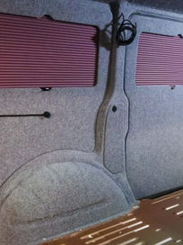 Van interior lining stage with grey carpeted walls and pink window blinds fitted
