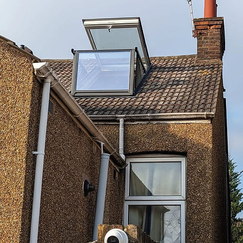 Open balcony roof window installed on a weathered tiled roof of a pebble dash house