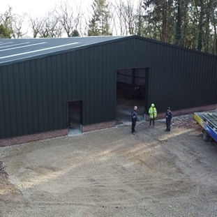 New dark grey steel commercial workshop building with delivery vans parked outside
