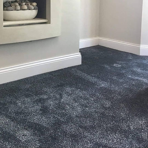 A close up view of newly fitted dark grey carpet with white skirting boards