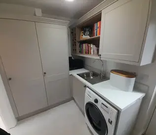 Cozy laundry room with grey cabinets, featuring a washing machine