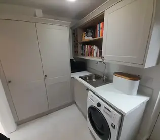Cozy laundry room with grey cabinets, featuring a washing machine