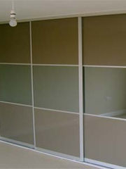 A minimalist room with a large sliding wardrobe featuring brown panels and white frames