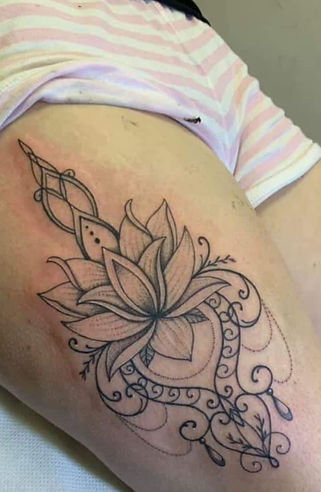 Tattoo of a detailed, elegant lotus flower with intricate swirls
