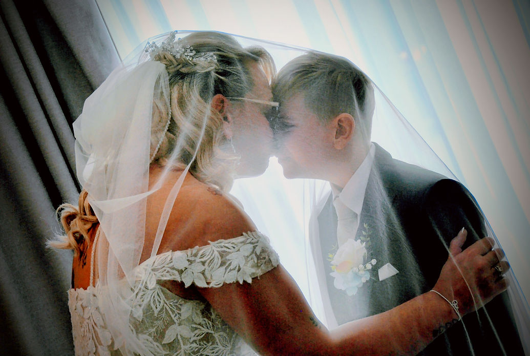 Bride and young boy share a joyful moment under a veil