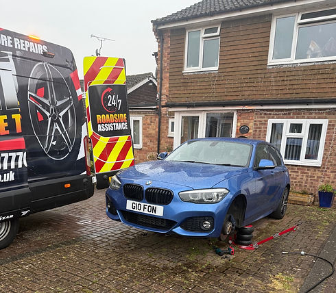 Blue car on driveway with a missing front wheel