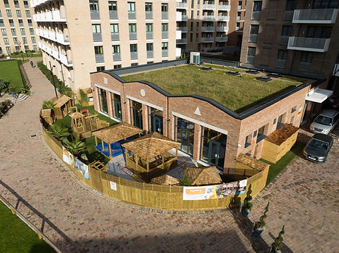 Aerial view of nursery building with green roof and outdoor play yard