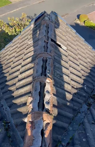 Aerial view of a damaged, old ridge tile on a tiled roof with exposed mortar and a gap