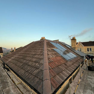 Wide view of a large dark tiled roof on a brick property with scaffolding installed