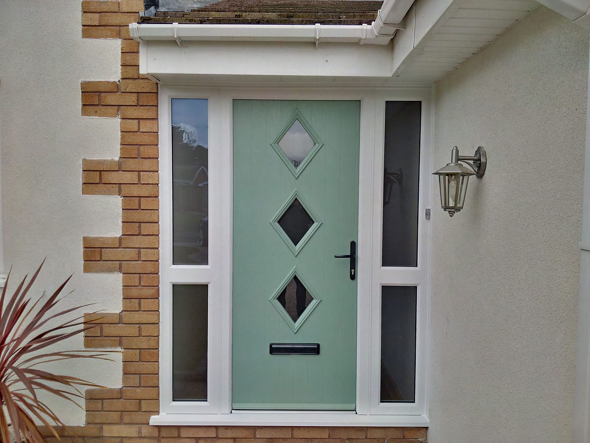 A pastel green front door with three diamond-shaped windows