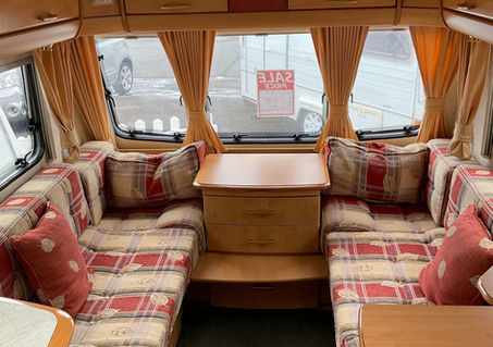 Front lounge of a caravan with parallel seating, chest of drawers and clock