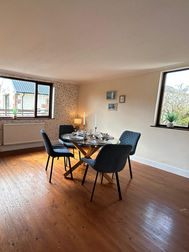 Staged dining room area with dark table blue chairs and wooden flooring   