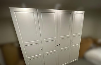 White four-door wardrobe with sleek panel design in a softly lit room