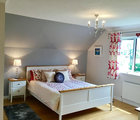 Beautifully staged bedroom with double bed, bedside lamps, and patterned curtains   