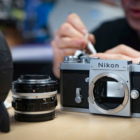 Vintage Nikon camera body and lens on a table during cleaning or servicing