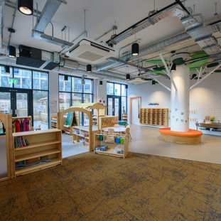 Open plan indoor play area with padded matting and wooden furniture
