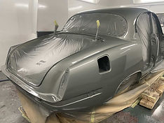 A classic car in a spray booth, wrapped in protective plastic