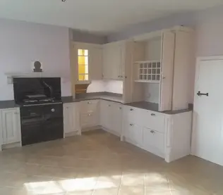 A spacious, empty kitchen with light cabinets, a dark stove