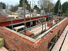 Construction site showing a partially built brick wall with scaffolding
