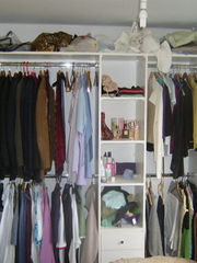 A neatly organized closet filled with various clothes on hangers