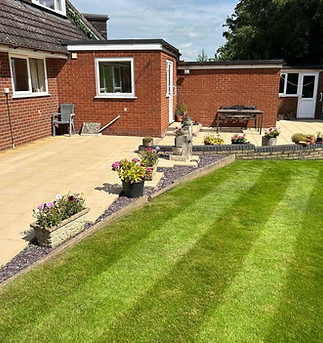 Well manicured lawn next to a brick house driveway
