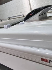 Close up view of a Fiamma F45s awning casing fitted onto the roof of a white van