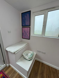Small corner room with wood effect flooring, a white steps unit and two framed pictures