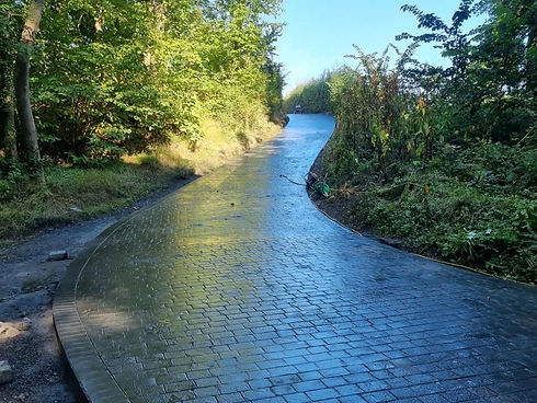 A freshly paved, curving brick path winds through a lush
