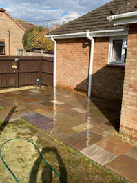 Newly laid patio paving flags next to a brick house and timber fence