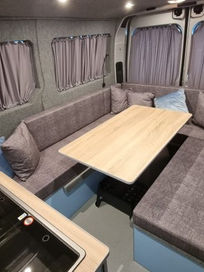 Finished large camper interior with U shaped grey seating long wooden table
