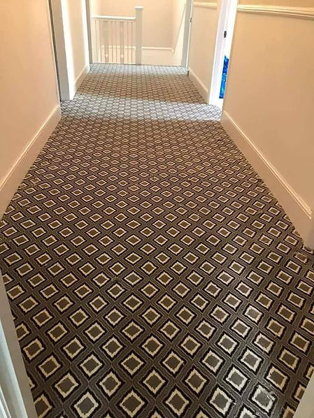 A hallway landing featuring a newly fitted brown and cream geometric patterned carpet