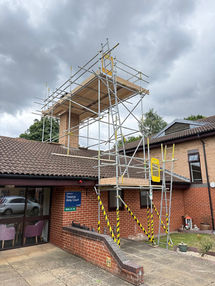 Free standing scaffold tower with secure working platform on a brick building exterior