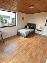Spacious bedroom area before staging with wooden ceiling panels and single bed