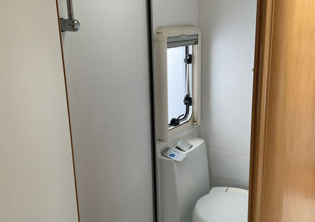 Caravan bathroom with white toilet and integrated shower cubicle