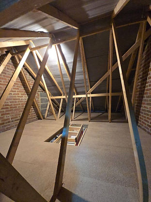 Exposed natural wood support beams and roof trusses in a bright attic space