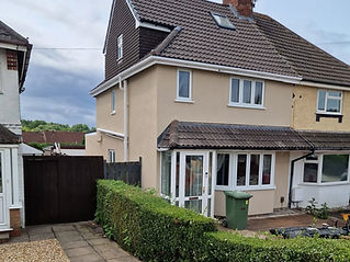Two-story beige house with dark roof tiles, white-framed windows