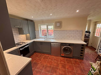 A kitchen with grey cabinets white countertops subway tile backsplash