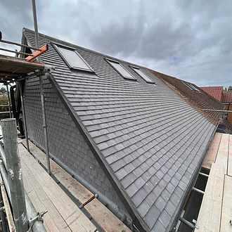 Newly tiled grey slate roof with three skylight windows installed
