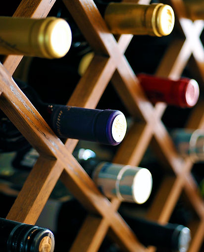 A wooden wine rack holds bottles in varying colors